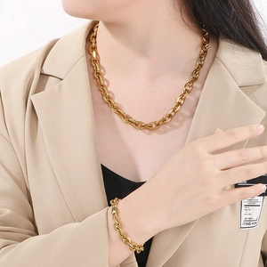 Détail de l'ensemble collier et bracelet en acier titane doré porté par un mannequin