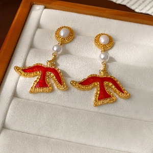 Detailed shot of vintage gold bird earrings with red enamel and pearls in a velvet tray
