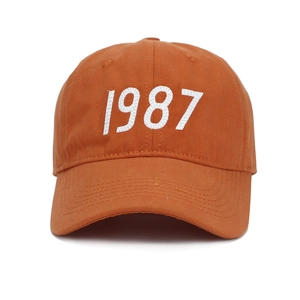Classic orange cotton baseball cap with white 1987 embroidery on a white background