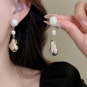Gros plan de boucles d'oreilles pendantes en perles baroques portées par un mannequin
