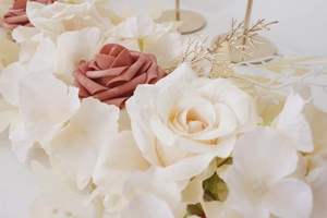 Detailed view of white and caramel artificial roses with gold decorative branches and petals