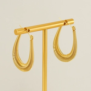 Golden teardrop hoop earrings with spiral texture on a gold jewelry display stand