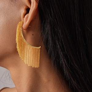 Macro detail of gold beaded fringe earrings with elegant metallic tassel chains