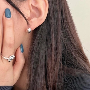 Close-up of minimalist S925 sterling silver bean stud earrings and ring worn by model