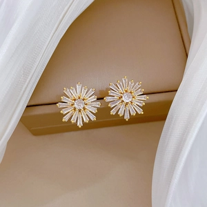 Elegant gold snowflake earrings set with radiant cubic zirconia crystals on jewelry box