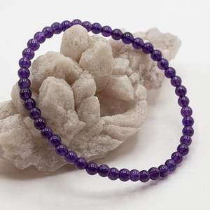 Minimalistisches 4mm Amethyst Armband präsentiert auf einem hellen Kristallcluster