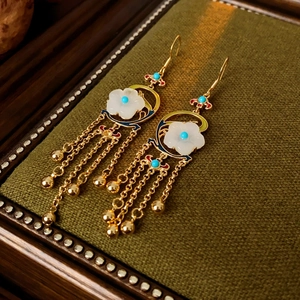 Detail of vintage gold-plated flower earrings with blue stone and long chain tassels