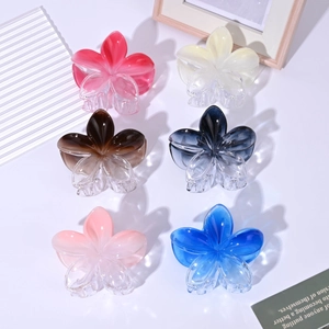 Flat lay of 8cm gradient plumeria hair claws in various translucent colors on a desk