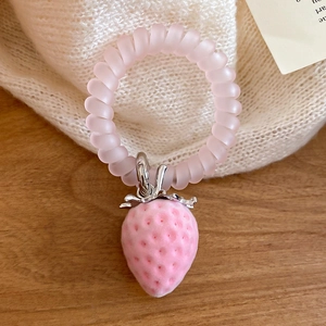 Gros plan sur l'élastique rose avec pendentif fraise givrée et détail de feuille argentée