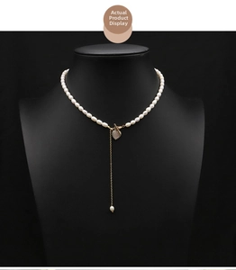 Detail showing natural pearl necklace with golden OT buckle and heart shell pendant tassel