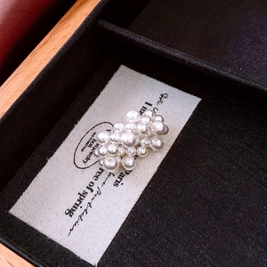 Close-up of white pearl cluster earrings in a velvet jewelry box with French aesthetic