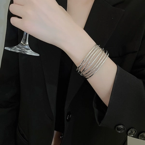 Close-up of stacked silver layered bracelets with twisted texture on a model's wrist
