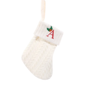 White knitted Christmas stocking with red embroidered letter A and festive leaf pattern