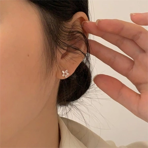 Close-up of minimalist S925 sterling silver flower stud earrings on model ear