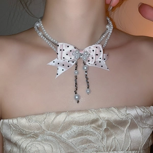 Detail of double-layer pearl choker with pink polka dot bow and delicate tassels