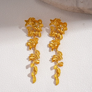 Vue détaillée de boucles d'oreilles dorées feuilles et fleurs sur surface texturée