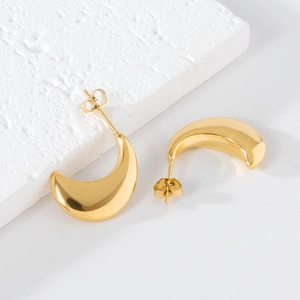 Macro shot of polished gold crescent stud earrings showing smooth metallic finish