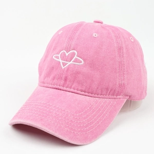 Close-up of pink washed canvas baseball cap with heart embroidery and vintage texture