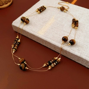 Détail d'un collier double rang avec perles œil de tigre et séparateurs dorés