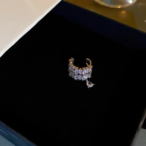 Macro detail of silver drop clip earring with sparkling zircon on black velvet background