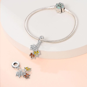 Detailed view of silver charm bracelet with yellow and orange maple leaf pendants