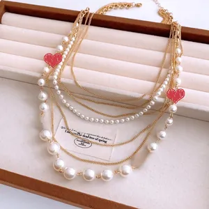 Detailed close-up of multi-layer gold chain necklace with pearls on a velvet jewelry tray