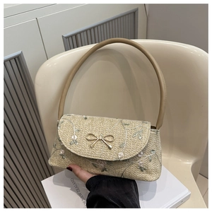 Close-up of floral embroidery and golden bow metal buckle on a woven shoulder bag