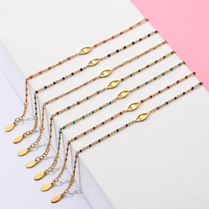 Set of seven gold stainless steel bracelets with colorful evil eye charms on a stand