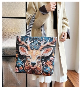 Detail of canvas tote bag featuring complex 3D elk embroidery and floral tapestry pattern