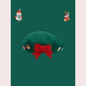 Close-up of dark green wool beret with red bow and festive Christmas charms details