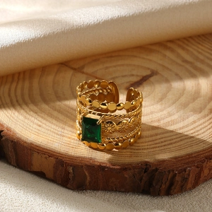 Detailed close-up of golden ring with emerald-cut green stone and textured band