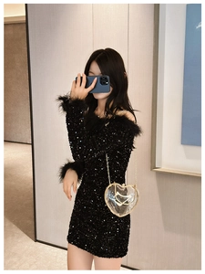 Mirror selfie showing the transparent heart-shaped chain bag with a black sequin feather dress