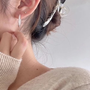 Close-up of minimalist silver oval hoop earring worn by a model in a lifestyle setting