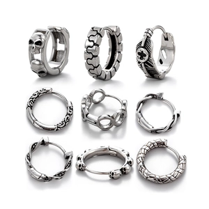 Detail of silver stainless steel hoop earrings with skull, cross, and feather patterns