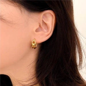 Close-up of gold knotted hoop earrings in geometric design worn by a female model