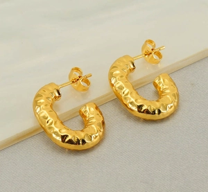 Detailed close-up of 18K gold-plated U-shape earrings with hammered texture and butterfly backs