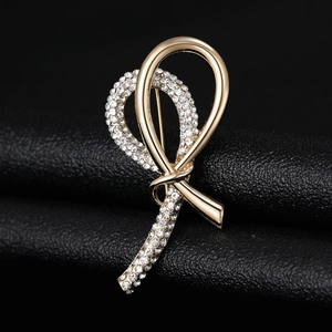 Detailed macro shot of a golden ribbon brooch with sparkling rhinestones on black texture