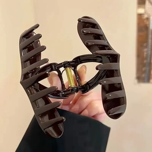 Elegant heart shaped dark brown hair claw clip held by hand showing spring detail