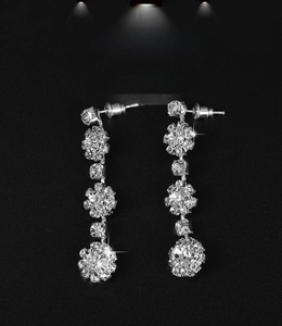 Macro shot of silver-tone floral drop earrings with sparkling rhinestones on black background