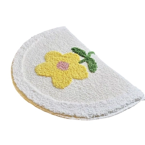 Semi-circular bathroom mat with yellow flower and green leaves on white faux cashmere
