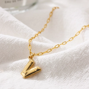 Macro shot of 18K gold V letter pendant necklace with unique embossed details
