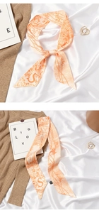 Detail of silk skinny scarf with vintage letter S print on peach satin fabric