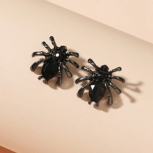 Macro detail of black spider earrings with gothic aesthetic and dark drop-shaped stone