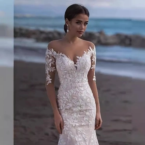 Elegant off-shoulder lace wedding dress with long sleeves and floral embroidery on beach