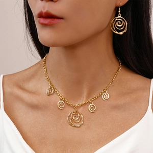 Detail of gold spiral rose necklace and matching earrings on model neck and ears