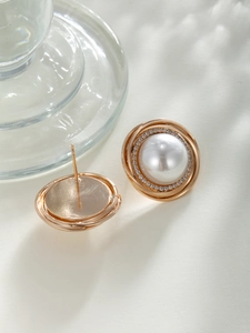 Detailed view of vintage pearl stud earrings with sparkling rhinestones and gold rings