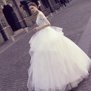 Elegant white lace wedding dress with puff sleeves and layered tulle skirt in forest style
