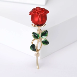 Elegant red enamel rose brooch with green leaves and gold stem on white background