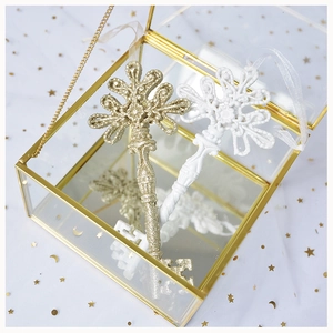 Detailed view of golden glitter and white matte key ornaments in a glass display box