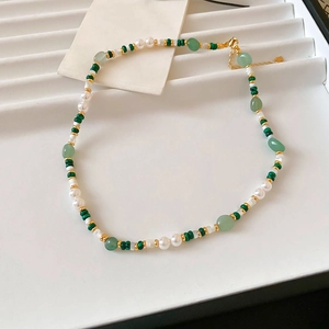 Detail of beaded necklace with green malachite, pearls, and gold clasp on jewelry tray